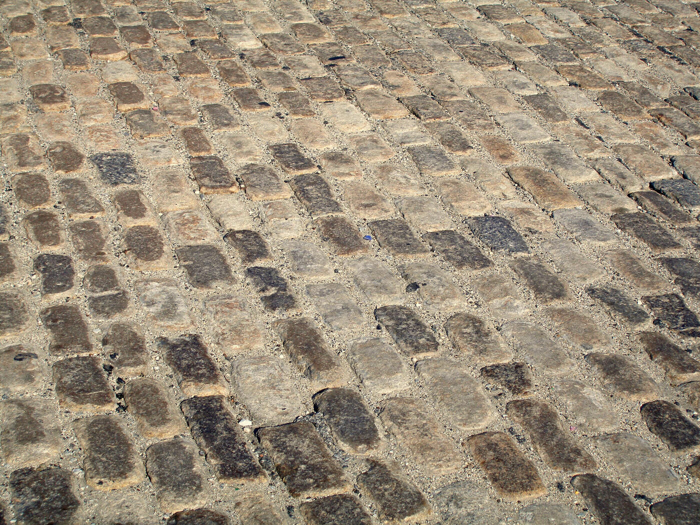 Close-up of warm-toned granite block paving setts laid in a fan pattern, showing the joints between the stones